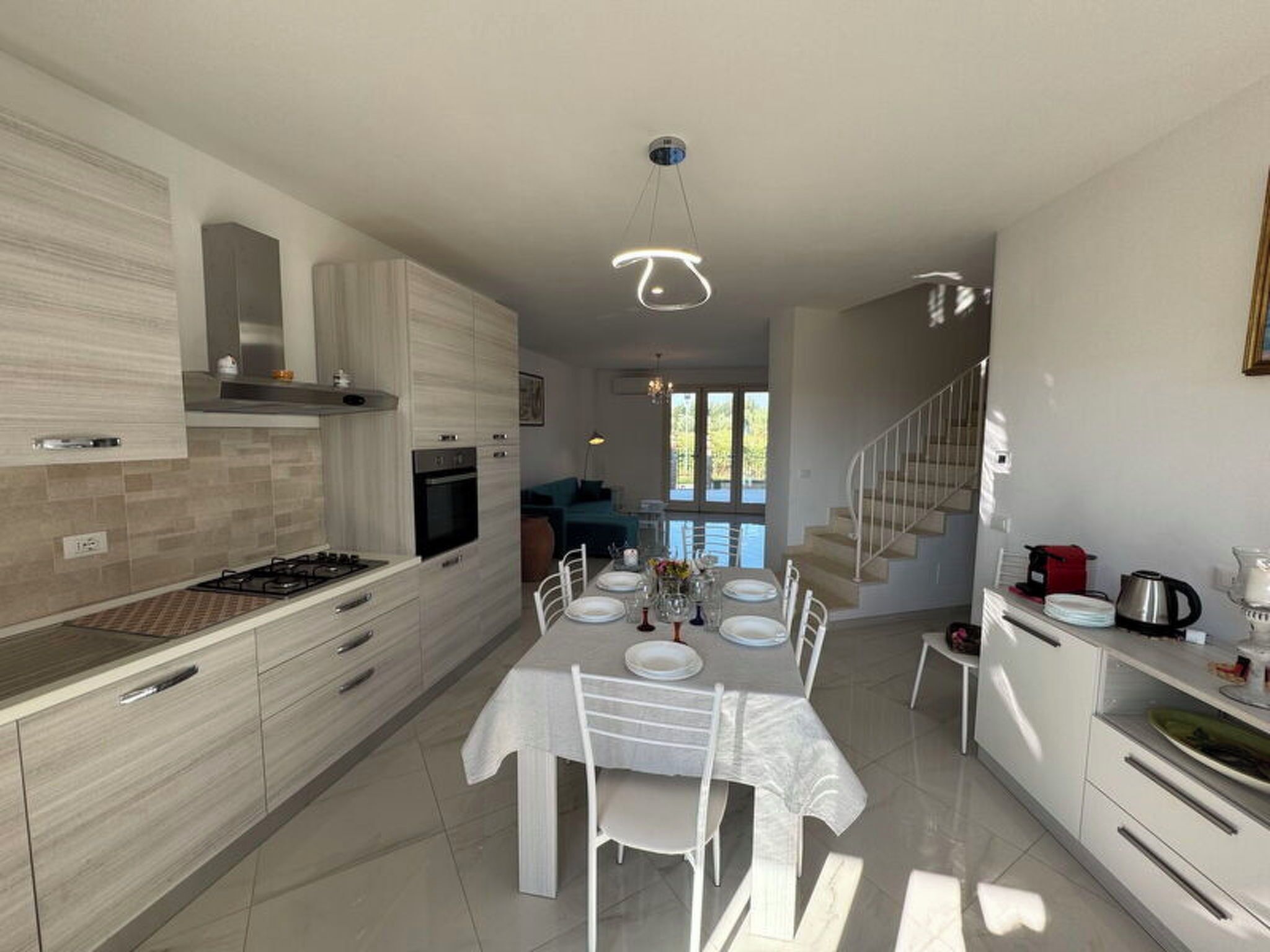 Une cuisine moderne avec un coin repas, un escalier et une vue sur l’extérieur.