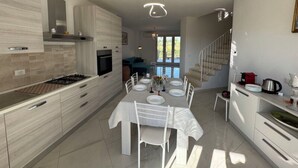 A modern kitchen with a dining area, a staircase, and a view of the outdoors. - Villa al Glicine Proprietà by Interhome (Altopascio)