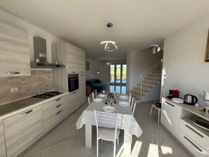 A modern kitchen with a dining area, a staircase, and a view of the outdoors. - Villa al Glicine Proprietà by Interhome (Altopascio)