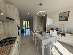 A modern kitchen with a dining area, a staircase, and a view of the outdoors. - Villa al Glicine Proprietà by Interhome (Altopascio)