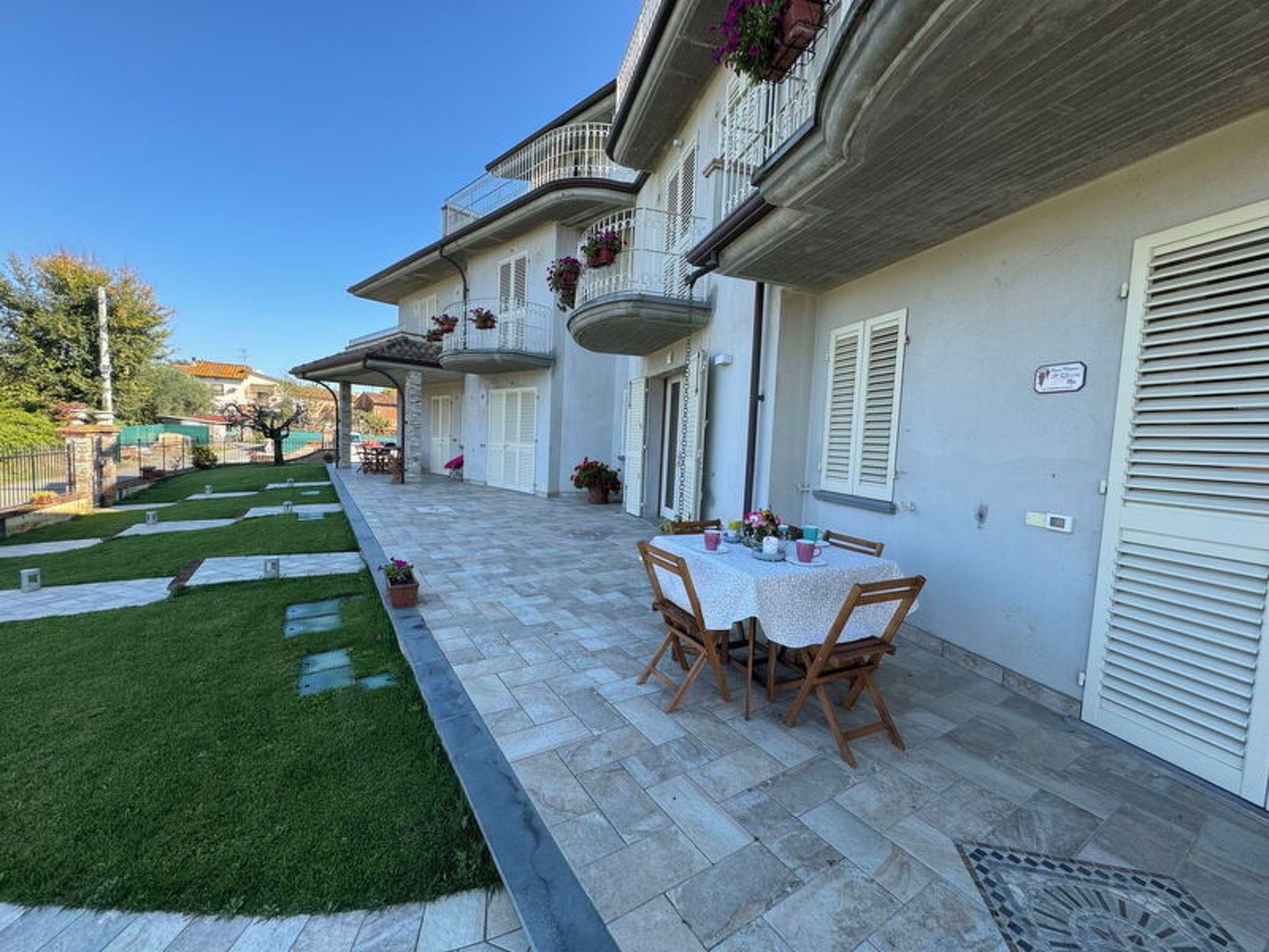 Ein zweistöckiges Haus mit Terrasse, Gartenmöbeln und einem gepflegten Rasen.