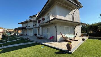 Ein zweistöckiges Haus mit Balkon, einer Terrasse mit Tisch und Stühlen und einer Hängematte.