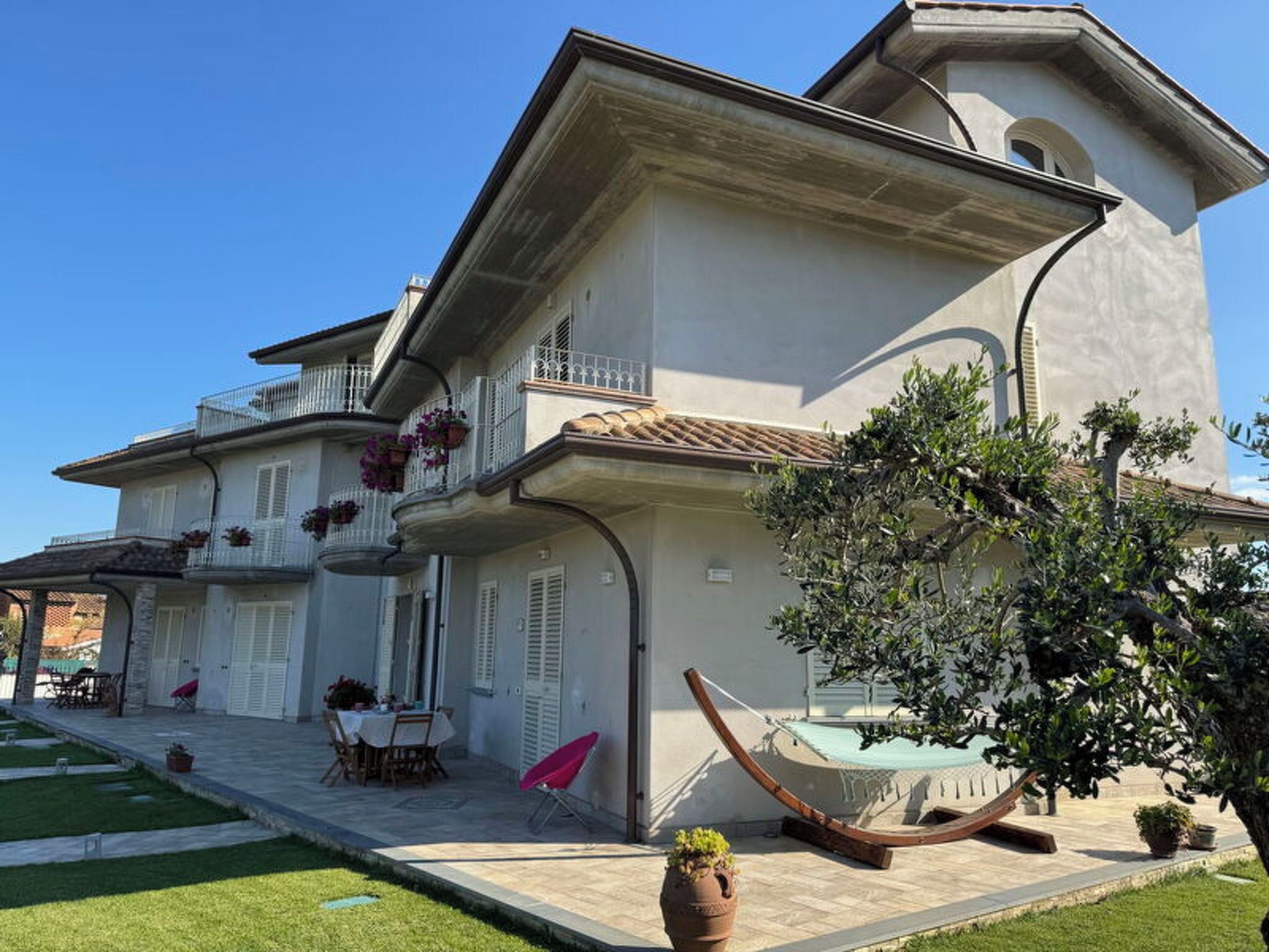 Un immeuble à plusieurs étages doté d’un balcon, d’un espace extérieur aménagé pour s’asseoir et d’un hamac.