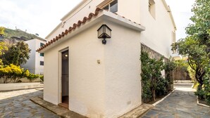 A building with a white exterior, a tiled roof, and a small entrance with a door. - 110 Port de la Selva - House close to the beach (Port De La Selva, El)