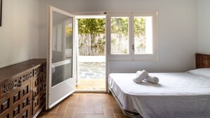 A bedroom with a bed, a wooden dresser, and a sliding glass door leading to an outdoor area. - 110 Port de la Selva - House close to the beach (Port De La Selva, El)
