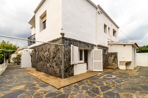 A two-story building with a stone facade, a balcony, and a small attached structure with shutters. - 110 Port de la Selva - House close to the beach (Port De La Selva, El)