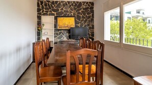 A dining area with a stone wall, a television, and a view of buildings through a window. - 110 Port de la Selva - House close to the beach (Port De La Selva, El)