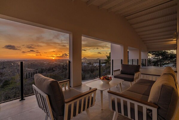 Ein moderner Außenbereich mit Sitzgelegenheiten und Blick auf einen Sonnenuntergang über einer Skyline.