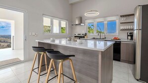 Une cuisine moderne dotée d’un grand îlot central, de tabourets de bar, d’un lave-vaisselle et d’un réfrigérateur.