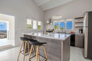 Eine moderne Küche mit einer großen Kochinsel, Barhocker, einer Spülmaschine und einem Kühlschrank.