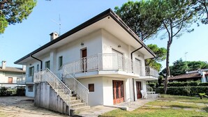 Uma casa de dois andares com varanda, escada e um jardim frontal.