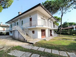 Ein zweistöckiges Haus mit Balkon, Treppe und Vordergarten.