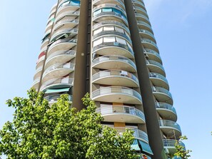 Ein Hochhaus mit zahlreichen Balkonen, von denen einige mit Geländern versehen sind und andere nicht.