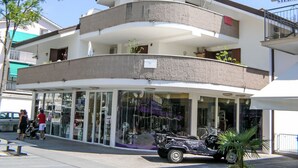 Edificio de dos plantas con una tienda en la planta baja y balcones residenciales en el nivel superior.