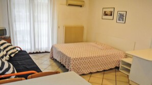 Een kamer met een bed, een tafel, een stoel, een radiator en een raam met gordijnen.