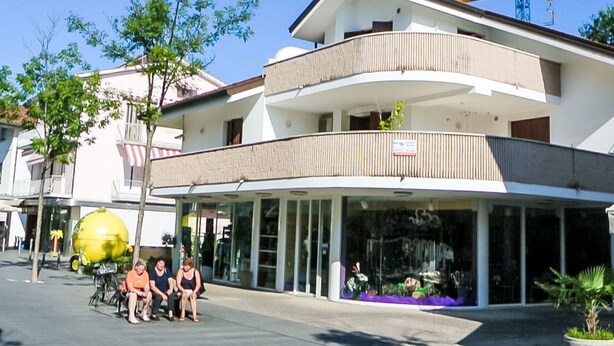 Een meerlaags hotel met een overdekte ingang en een balkon op de bovenste verdieping.