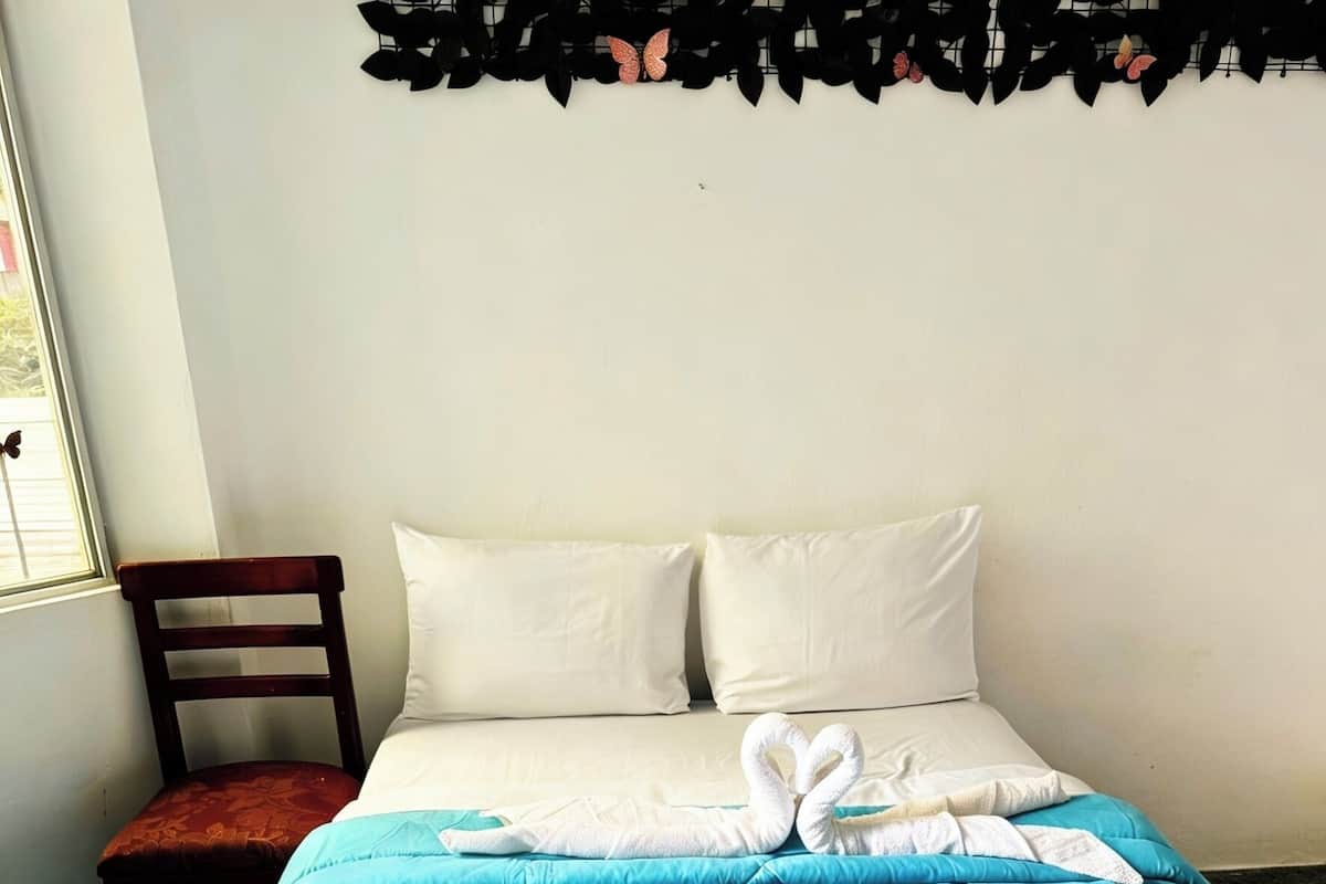 A hotel room with a bed, a chair, and a window.