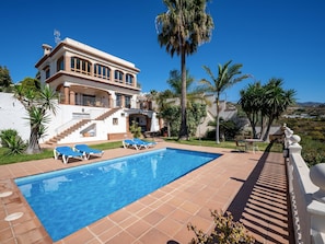 Une grande maison avec une piscine, un escalier et du mobilier d’extérieur.
