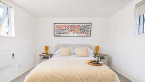 A bedroom with a bed, two bedside tables, a framed picture, and a breakfast tray.