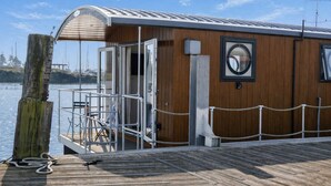 A wooden boat with a covered deck, a small open door, and a rope barrier.