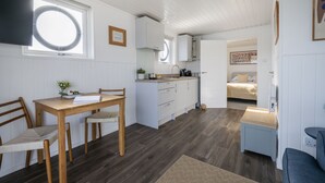 A compact kitchen with white cabinets, a wooden dining table, and a small island.