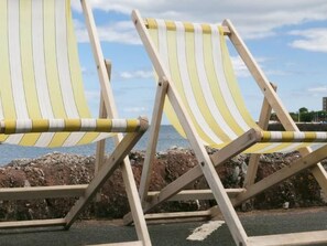 Two striped beach chairs with a rocky shoreline and a clear sky in the background. - in Torquay by Interhome (Torquay)