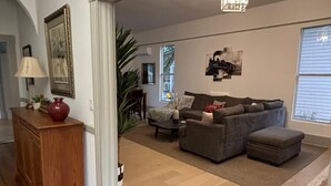 Un salon avec un canapé, un pouf et une lampe posée sur un meuble en bois.