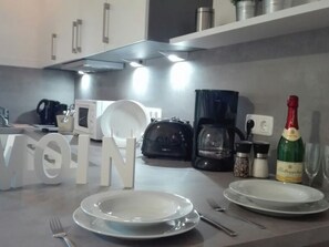 Eine Küche mit weißen Schränken, einer Kaffeemaschine, einer Champagnerflasche und einem großen dekorativen Schild.