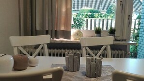 Ein Essbereich mit Tisch, Stühlen und Blick auf einen Garten durch ein Fenster.