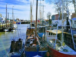 Ein Yachthafen mit verschiedenen vertäuten Booten, darunter ein blaues Boot mit der Aufschrift 'BUS 39' und ein weißes Boot mit 'LARA LAUKE'.