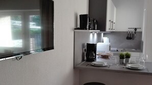 Eine moderne Küche mit Flachbildfernseher, Kaffeemaschine, Mikrowelle und zwei Barhocker.