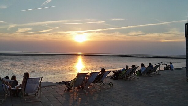 Ein Sonnenuntergang mit Strandstühlen und ruhiger See.