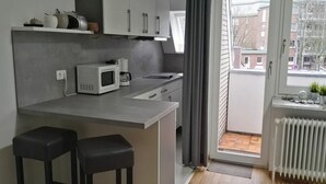 Eine moderne Küche mit einer zentralen Kochinsel, zwei Barhocker, einer Mikrowelle und einer Kaffeemaschine.