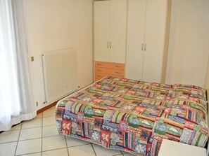 A bedroom with a bed, a wardrobe, and a radiator. - Wohnung im Zentrum von Lignano Sabb. "Maria 1 by Interhome (Lignano Pineta)