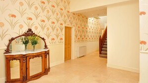 A hallway with patterned wallpaper, a wooden console table with a mirror, and a staircase. - Modern eingerichtete Ferienwohnung in der ersten Etage mit Panorama-Meerblick v by Interhome (Torquay)
