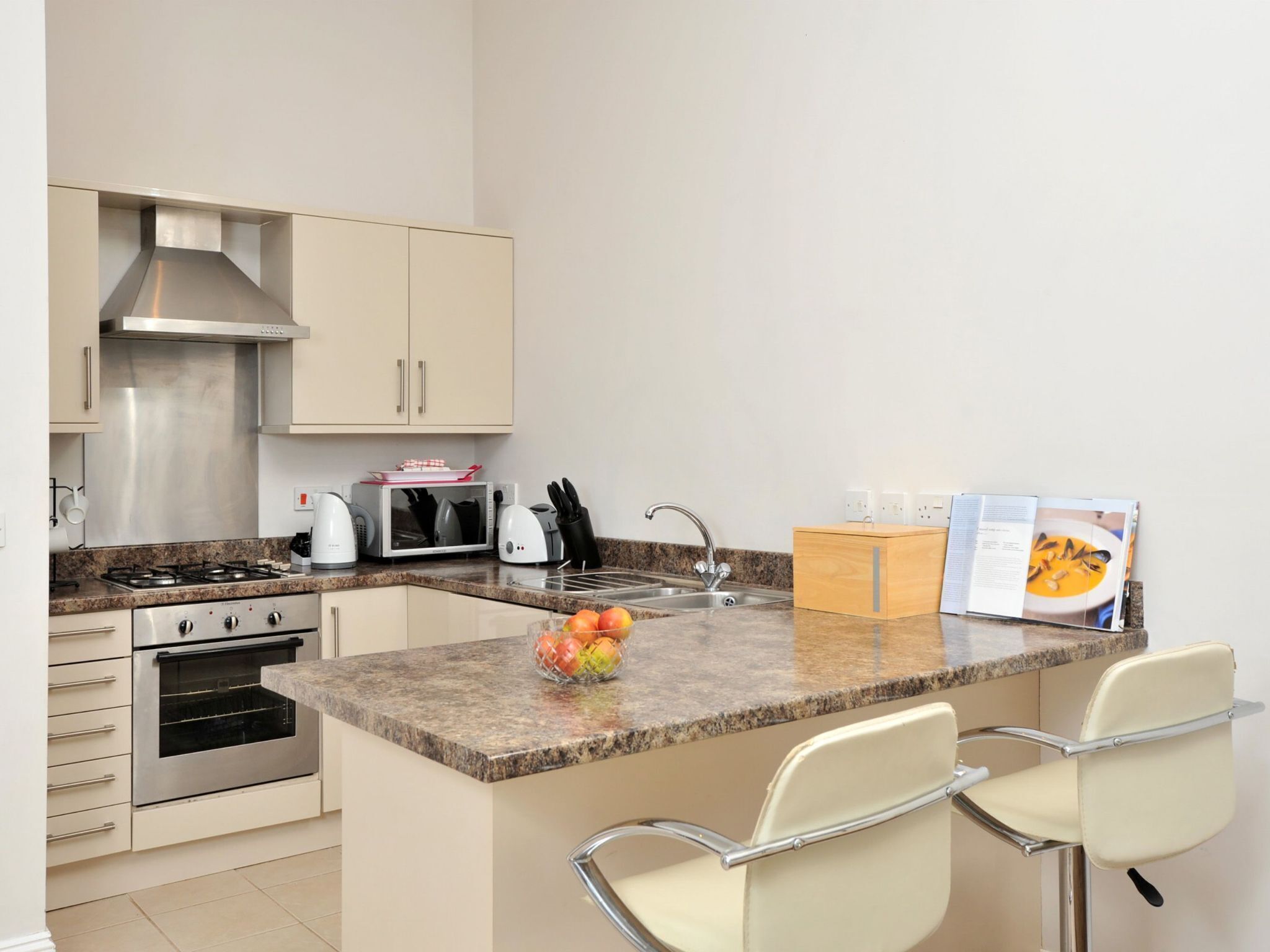 Una cucina moderna con isola centrale, elettrodomestici in acciaio inossidabile e uno sgabello da bar.