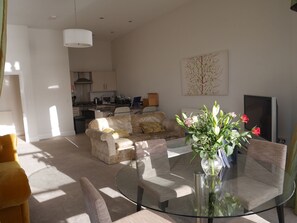 A modern living room with a glass dining table, a sofa, and a kitchen in the background. - Apartment mit Balkon für vier Personen by Interhome (Torquay)
