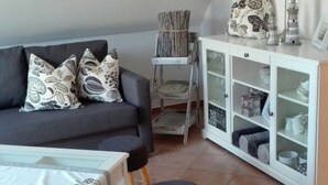 A living room with a sofa, a small table, a cabinet, and a stool. - Wat(t) ne Wohnung by Interhome (Büsum)