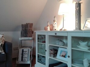 Ein Zimmer mit einem weißen Schrank, der Gläser, ein gerahmtes Bild und ein Schild mit der Aufschrift 'WILKOMMEN' beherbergt.