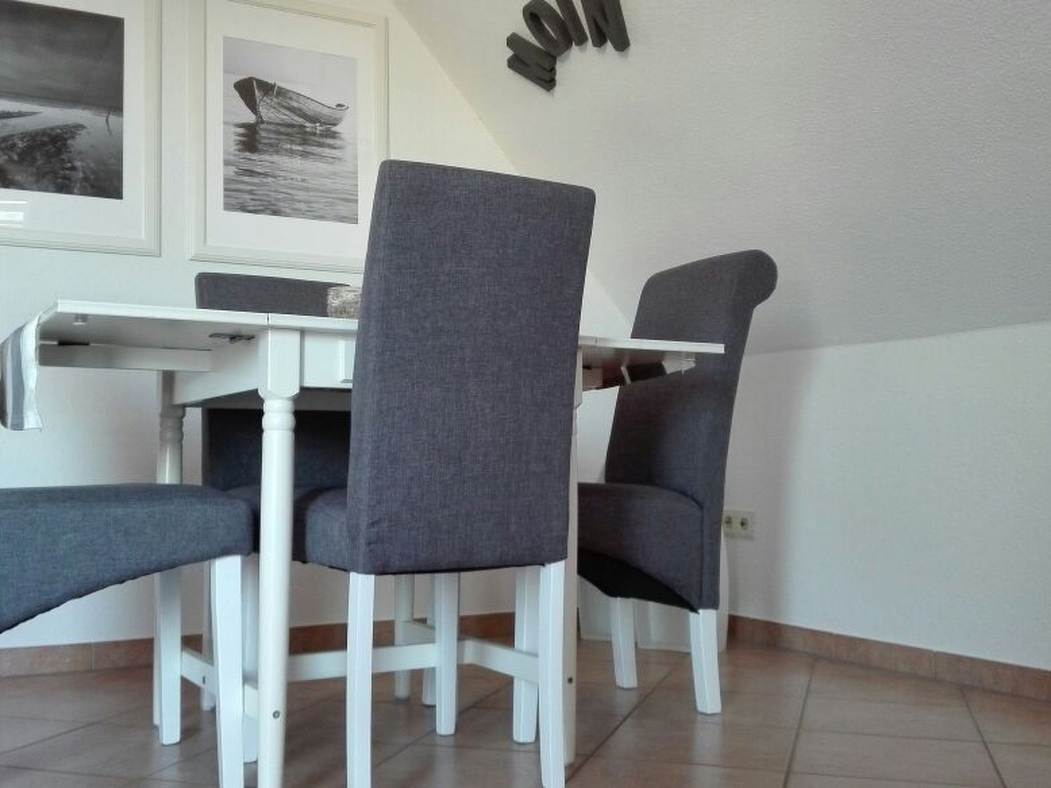 A dining area with a white table and four grey chairs.