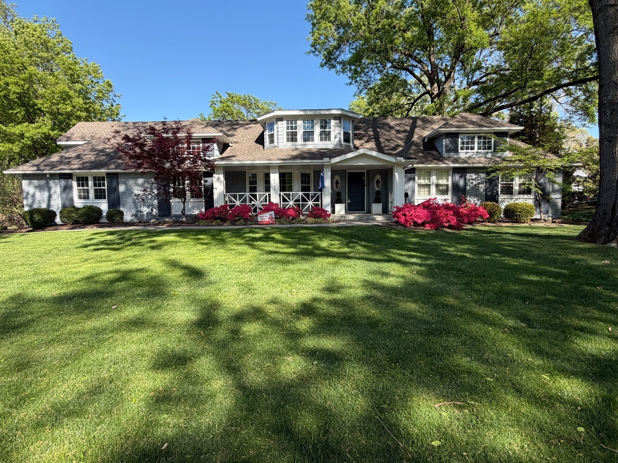 A two-story house with a front porch, a garage, and a well-maintained lawn.