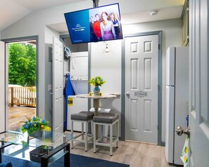 A compact kitchen with a TV, a small table with stools, and a door labeled 'BATHROOM'. - Cozy Two Bedroom Duplex Apartment (Autauga County)