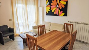 A living room with a wooden dining table, two chairs, a sofa, and a coffee table. - Billa 2 in grüner Lage by Interhome (Lignano Sabbiadoro)