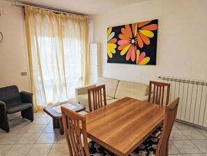 A living room with a wooden dining table, two chairs, a sofa, and a coffee table. - Billa 2 in grüner Lage by Interhome (Lignano Sabbiadoro)