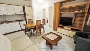 A compact living space with a kitchenette, dining area, and a seating area with a television. - Billa 2 in grüner Lage by Interhome (Lignano Sabbiadoro)