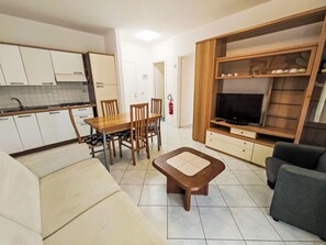 A compact living space with a kitchenette, dining area, and a seating area with a television. - Billa 2 in grüner Lage by Interhome (Lignano Sabbiadoro)