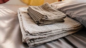 Un lit bien fait, avec des couvertures soigneusement pliées et une tête de lit en bois.
