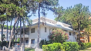 A two-story building with a balcony, surrounded by trees and a well-maintained garden. - Gemütliche Ferienwohnung Billa 7 by Interhome (Lignano Sabbiadoro)