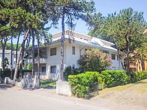 A two-story building with a balcony, surrounded by trees and a well-maintained garden. - Gemütliche Ferienwohnung Billa 7 by Interhome (Lignano Sabbiadoro)