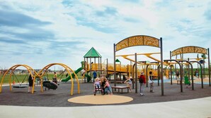 A playground with swings, slides, and climbing structures. - Lib3rtie Suites -2BR Family Suite •Sleeps 6 •Full Kitchen •Laundry •Free Parking (Saskatoon)